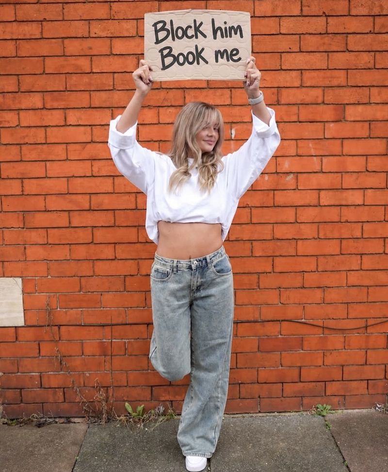 Casey holding a sign reading Block him, book me