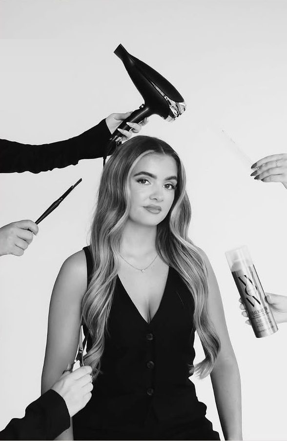 Casey of C.K.HAIR surrounded by a hairdryer, brush and styling tools